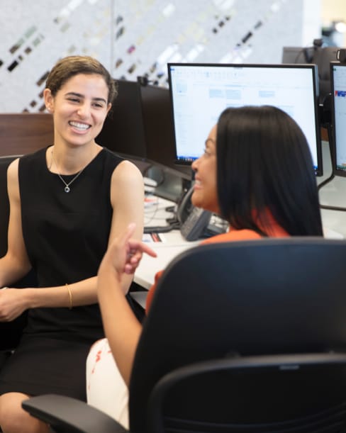 Two women sitting at a workstation and smiling